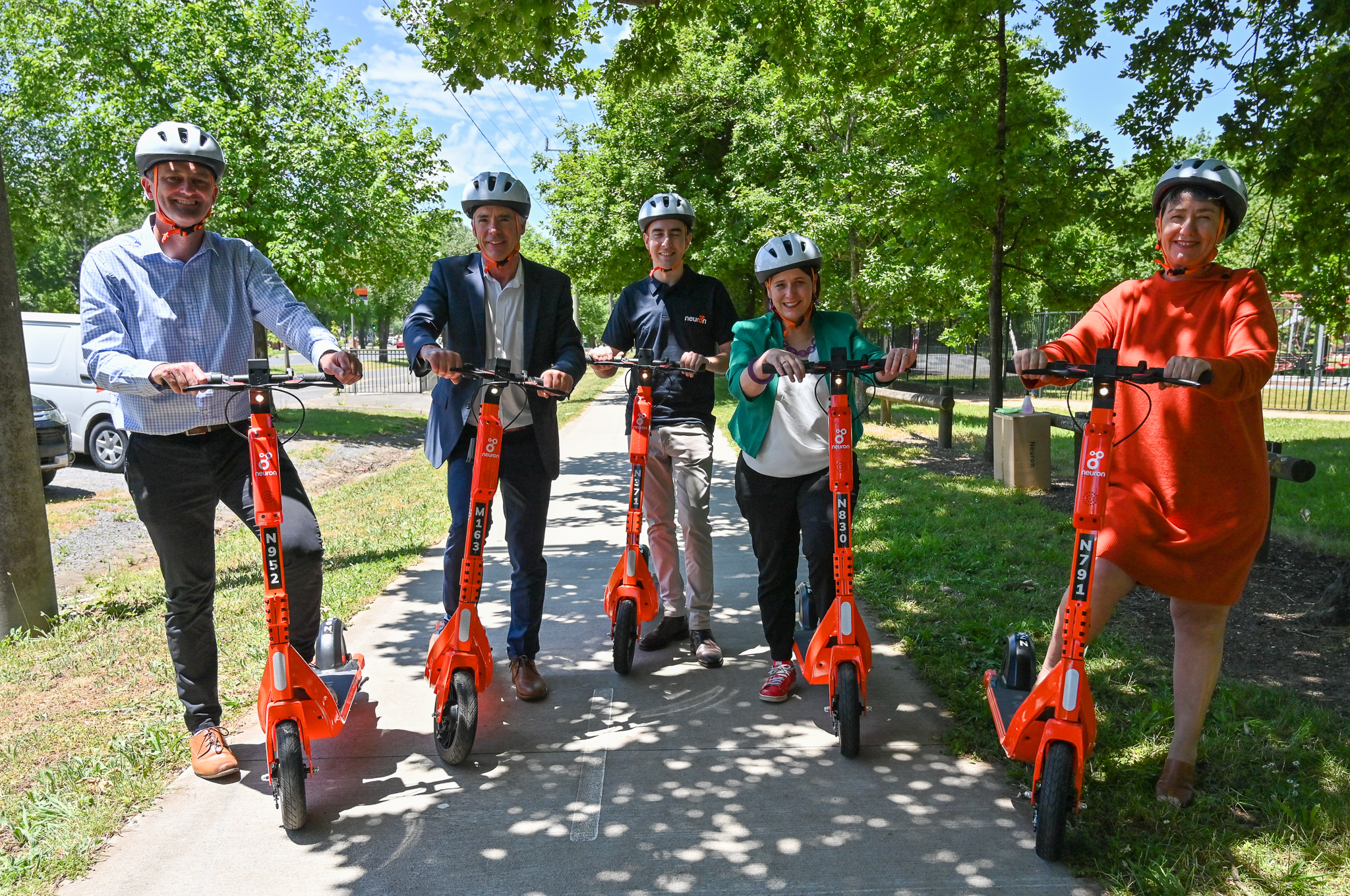 Cr Daniel Moloney, Michael Poulton, Richard Hannah, Julianna Addison, and Michalea Settle on orange e-scooters at Victoria Park
