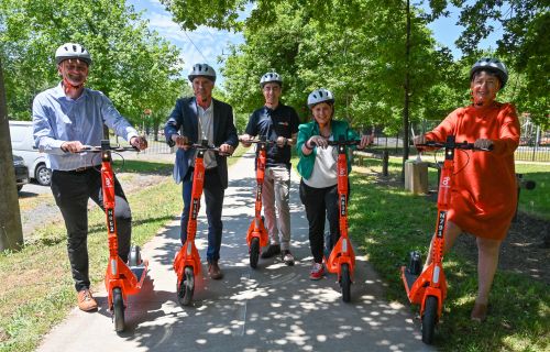 Cr Daniel Moloney, Michael Poulton, Richard Hannah, Julianna Addison, and Michalea Settle on orange e-scooters at Victoria Park