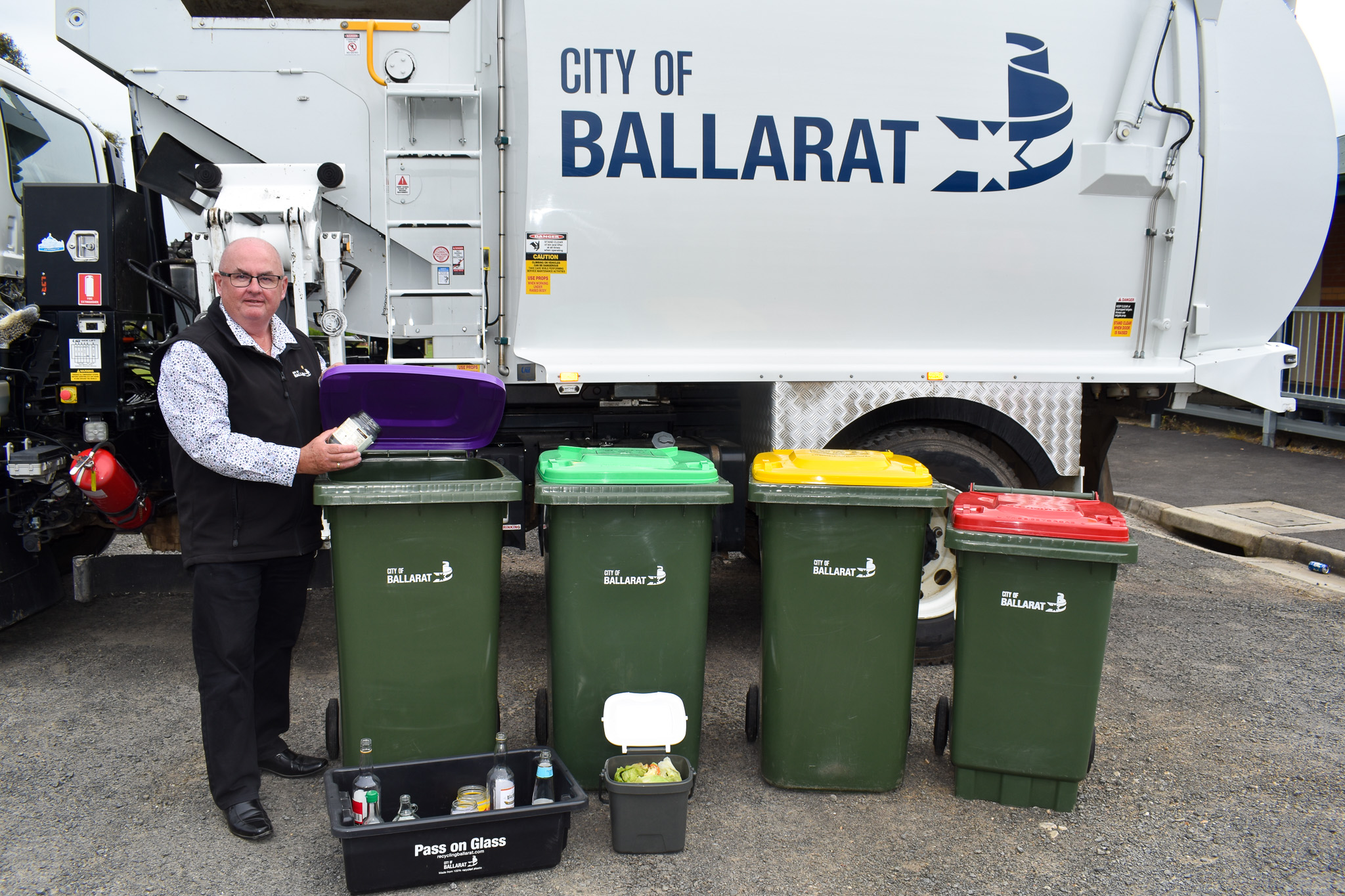 Cr Des Hudson with 4 bins in front of a city of ballarat rubbish truck