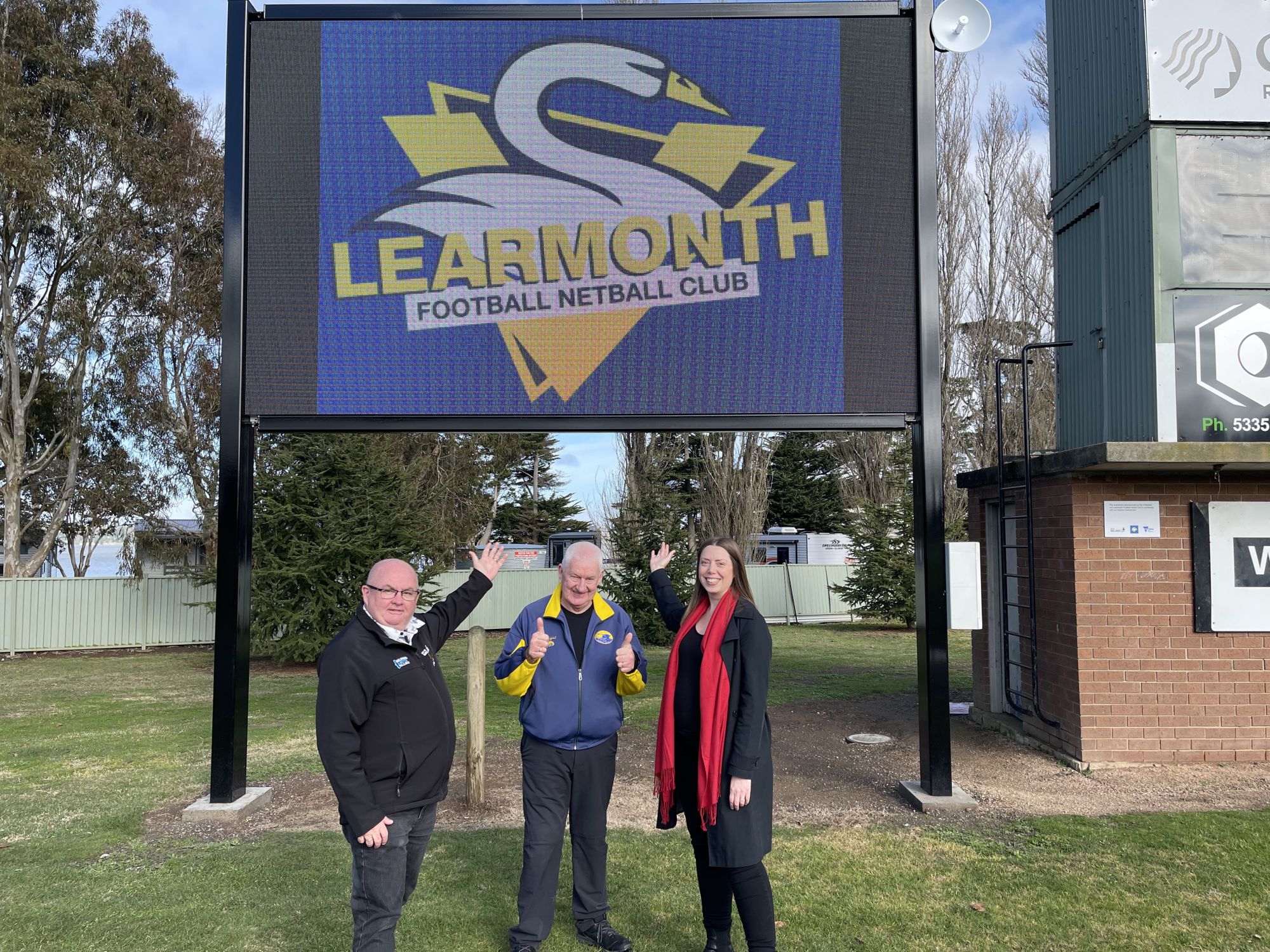 City of Ballarat Mayor Cr Des Hudson, Learmonth Football Netball Club life member Paul Ryan, and Member for Ripon Martha Haylett underneath the new scoreboard.