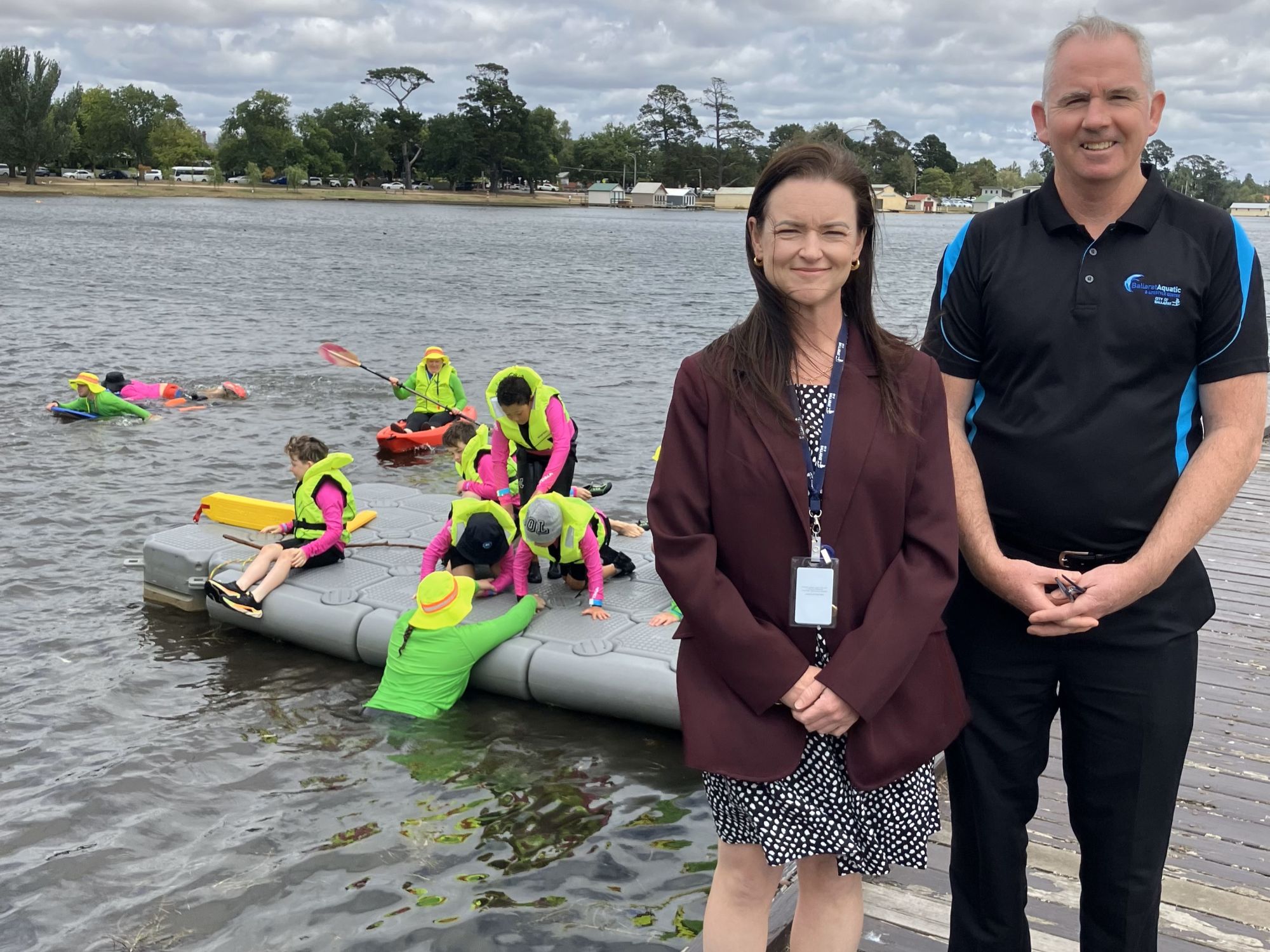 City of Ballarat Mayor and Leisure Services Manager at Lake Wendouree with children swimming in background.