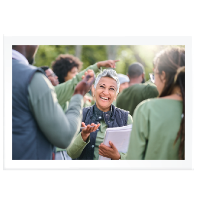 image of lady holding a pen and clipboard, standing with a community group