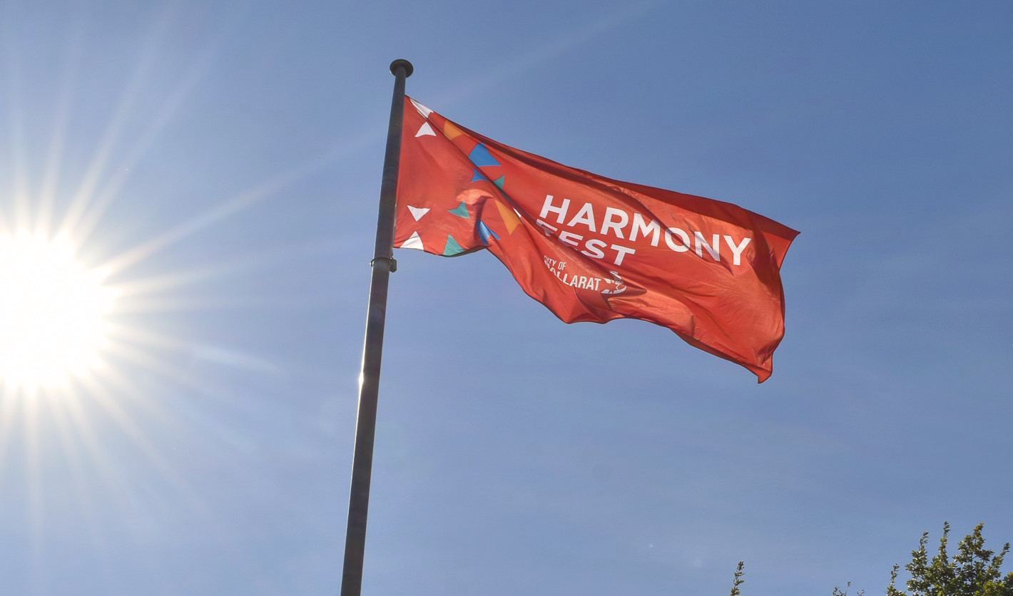 image of the ballarat harmony fest flag, flying on a blue sky