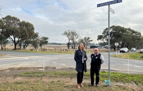 Catherine King and Des Hudson standing road side next to a street sign