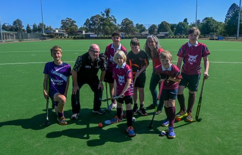 City of Ballarat Councillor, Cr Des Hudson with Hockey Ballarat president Jo Shepherd and junior hockey players on the new synthetic pitch at Prince of Wales Park.