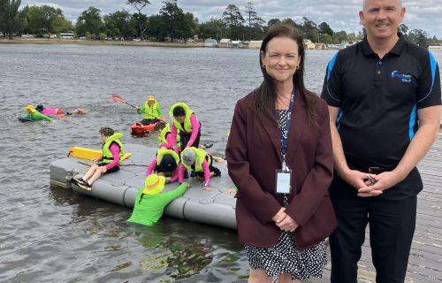 City of Ballarat Mayor and Leisure Services Manager at Lake Wendouree with children swimming in background.