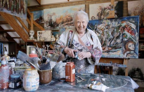 An old woman smiling in an artist studio