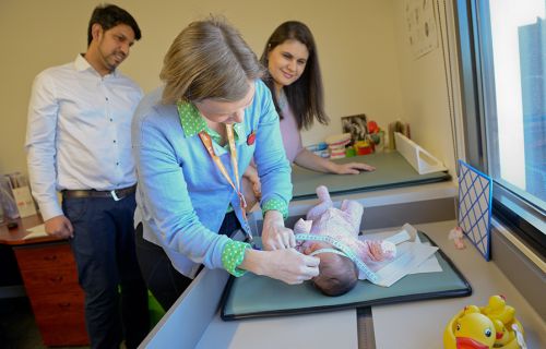 Nurse measuring baby with family