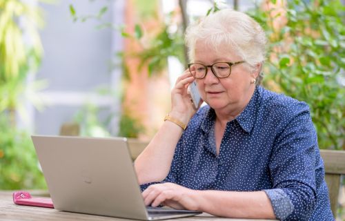 Women over 50 at a laptop while one the phone 