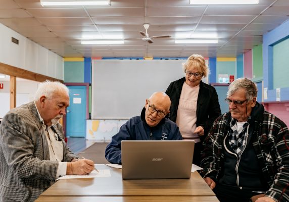 Generic photo group of people around a table working on a computer