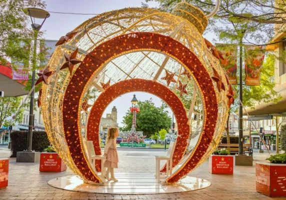 A giant red and gold Christmas bauble display, with a small doorway for people to walk through. to walk 