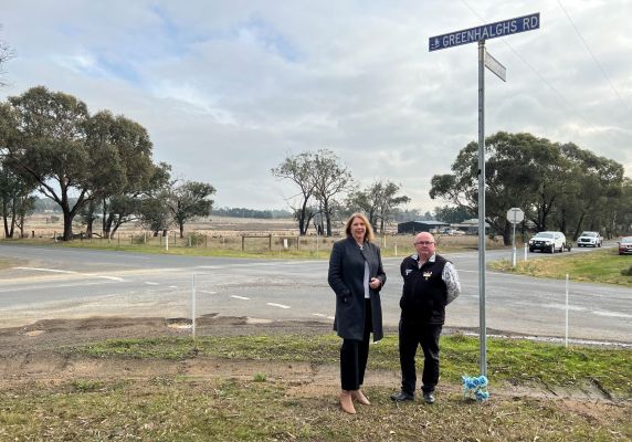 Catherine King and Des Hudson standing road side next to a street sign