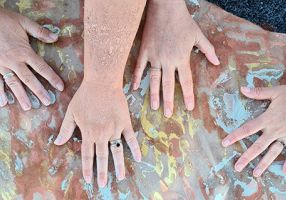 Four hand on a rock with painted hand prints underneath
