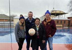 netballer, Mayor, Local Minister and President of Redan Football Club stand with a netball in front of the brand new netball courts and lights at City Oval