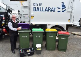 Cr Des Hudson with 4 bins in front of a city of ballarat rubbish truck
