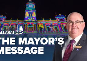 Text with The Mayor's Message with an image of Mayor Cr Des Hudson in front of the Town Hall display for White Night