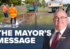 Text with The Mayor's Message with an image of Mayor Cr Des Hudson in front of footpath construction